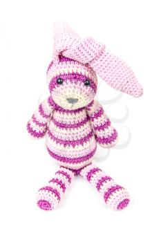 Knitted rabbit toy is sitting with knotted ears over white background with soft shadow