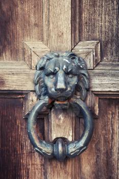 Old doorknob in shape of lion head on vintage wooden door, vintage tonal correction filter