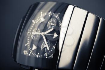 Luxury mens chronograph watch made of black high-tech ceramics lays on dark backdrop. Closeup studio photo with tonal filter and selective focus