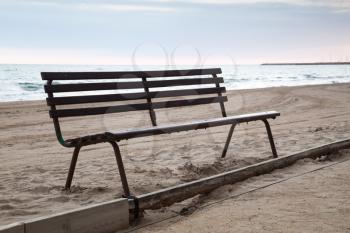 Old wooden bench stands on sandy beach, Mediterranean sea coast, Spain