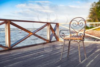 Wrought-iron chair standing on wooden seaside terrace