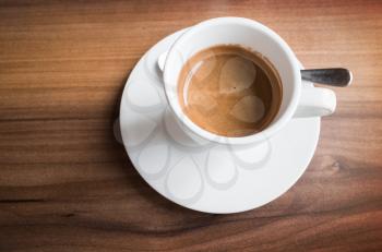 Freshly brewed espresso coffee in a white cup on saucer with spoon. Closeup photo with selective focus