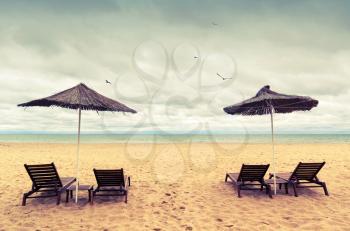 Sunbeds and umbrellas on empty sandy beach. Toned photo