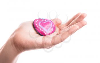 Pink painted handmade heart shaped stone in woman's hand isolated on white