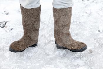 Male feet with traditional Russian felt boots on winter snowy road