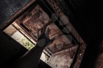 Grunge dark interior with open rusted door and male hand silhouette
