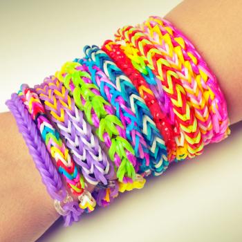 Colorful rubber rainbow loom band bracelets on wrist, trendy kids fashion accessories.  Vintage retro tonal photo filter correction