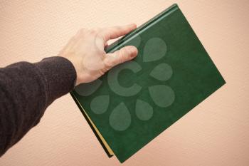 Book with empty dark green leather cover in male hand, retro style warm tonal correction photo filter effect
