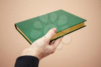 Book with empty dark green leather cover in male hand, old style warm tonal correction photo filter effect