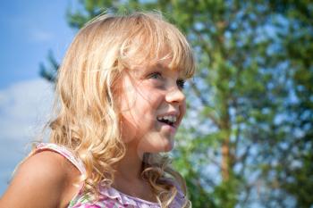 Portrait of a smiling little blond beautiful Russian girl above nature outdoor background