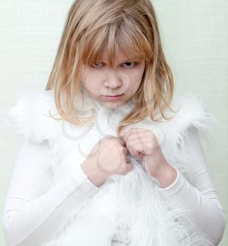 Little angry blond girl wears white fluffy fur vest