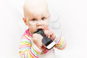 little baby baby chews on a mobile phone in colorful clothing