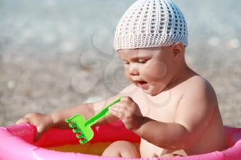 Outdoor summer portrait of Caucasian baby girl playing on the beach