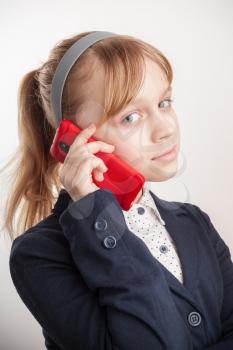 Blond Caucasian schoolgirl calling by mobile phone on white background