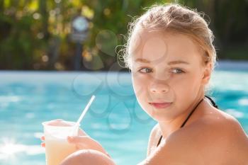 Little blond girl with cocktail in swimming pool