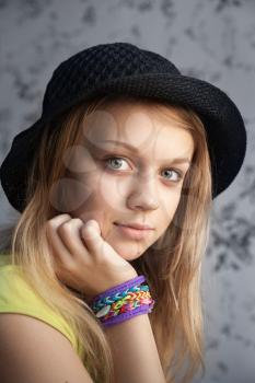 Portrait of beautiful blond teenage girl in black hat and rubber loom bracelets, vintage toned photo filter, instagram style effect