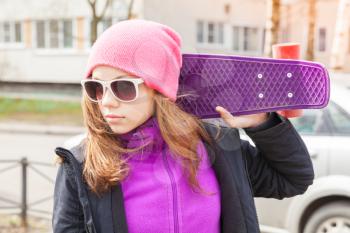 Blond beautiful teenage girl in sunglasses with skateboard, outdoor portrait