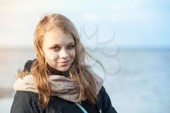 Closeup outdoor portrait of smiling beautiful blond Caucasian teenage girl on a Sea coast