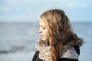 Closeup outdoor portrait of beautiful blond Caucasian teenage girl on a Sea coast with natural sun light