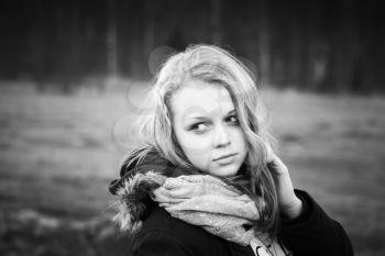 Closeup outdoor portrait of beautiful blond Caucasian teenage girl in a spring forest, black and white stylized photo