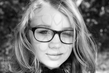 Beautiful blond Caucasian teenage girl in glasses, outdoor monochrome portrait