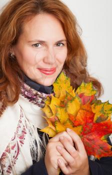 Closeup portrait of beautiful Young Caucasian woman in traditional Russian neck scarf with colorful autumn maple leaves