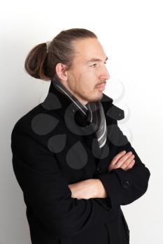 Closeup vertical studio portrait of serious young Asian man in black coat and woolen scarf over white wall background