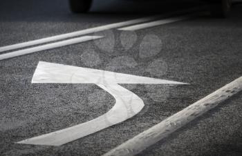 Road marking. White turning arrow and lines on dark asphalt.