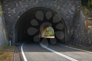 Dark automotive tunnel on turned rural asphalt road