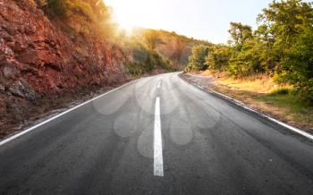 Empty rural asphalt highway perspective with bright shining sun