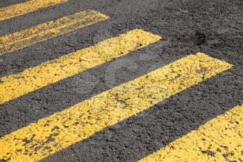 Pedestrian crossing road marking, yellow lines on gray asphalt