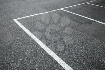 Empty slots on urban parking lot, white marking lines over gray asphalt pavement
