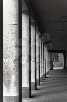 Abstract empty concrete interior background, dark urban corridor with columns, vertical photo with selective focus