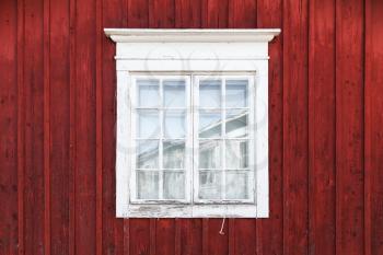 Old red wooden wall with window in white frame, typically Scandinavian living house architecture detail