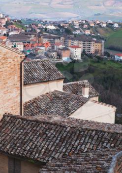 Cityscape of Fermo, Italy. Vertical photo with old tiling roofs of stone living houses