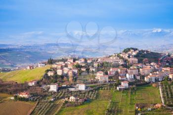 Bright rural panorama of Italian countryside. Province of Fermo, Italy. Village on a hill under blue cloudy sky