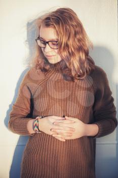 Beautiful blond teenage girl  in glasses and warm sweater, vertical close up outdoor portrait