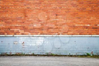 Abstract empty urban background, old red brick wall with gray tiling decoration near asphalt road