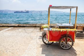 Red selling cart with boiled and roasted corn stands on empty coast of Bosphorus. Istanbul, Turkey
