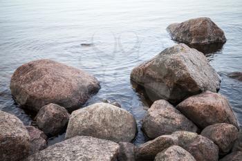 Dark coastal stones lay in still lake water