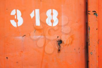 Grungy red metal wall with white number 318 label, industrial background photo