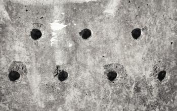 Grungy gray concrete block wall texture with technological holes