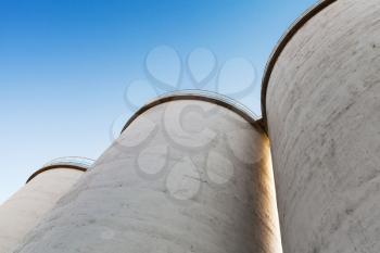 Industrial architecture fragment, large tanks made of concrete for storage of bulk materials under blue sky