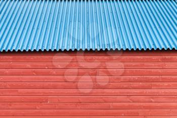 Red wooden wall under blue metal roof, background photo texture