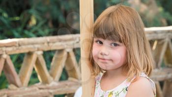 Cute Caucasian little girl standing on balcony, close-up outdoor portrait