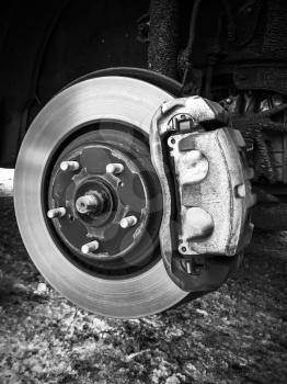 Replacing wheel on modern car, close-up black and white photo of rotor disk with brake