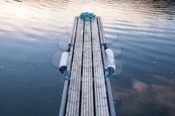 Perspective of small floating pier on still water, European marina, equipment for yachts mooring