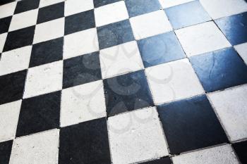 Old stone floor tiling with classical black and white checkered pattern