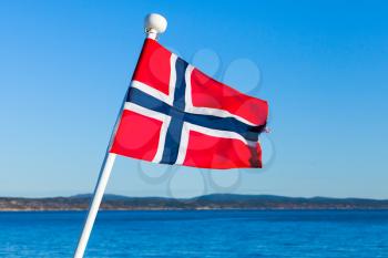 Flag of Norway over sea and blue sky background