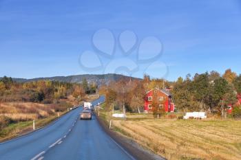 Car goes on the turning rural highway in autumn season, Norwegian countryside
